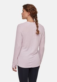Lichtroze langärmelige blouse met een ronde halslijn en zachte textuur. Heeft een centrale naad op de rug en aansluitende manchetten.