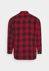 Chemise en flanelle à carreaux rouges et noirs à manches longues, vue de dos avec poignets boutonnés et col classique.