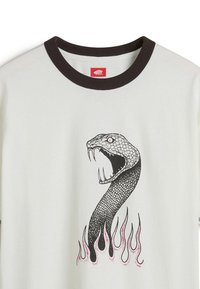 Camiseta de algodón blanca con un cuello acanalado marrón que presenta un gráfico de una serpiente negra y rosa rodeada de llamas en la parte inferior.
