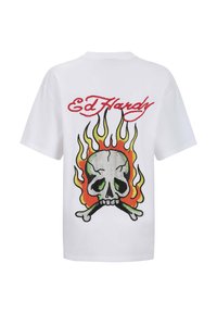 Bílý tričko s krátkým rukávem, na kterém je barevná lebka obklopená plameny, s textem "Ed Hardy" v červené barvě nad designem.