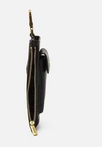 Cartera de cuero negro con superficie texturizada, equipada con cremallera y herrajes dorados. Diseño compacto con cierre de broche.