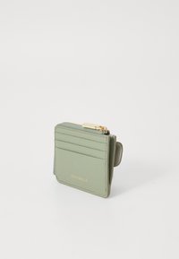 Porte-cartes en cuir vert avec un compartiment zippé, quatre emplacements pour cartes, une texture lisse et un logo doré sur le devant.