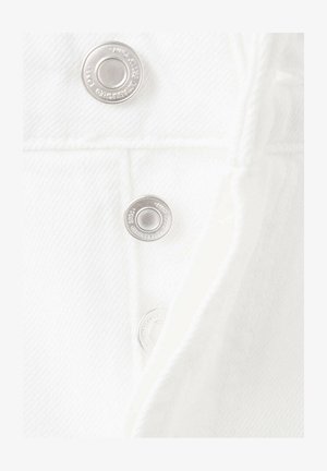 Close-up of white denim fabric with three visible silver snap buttons along a seam detail.