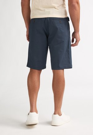 Navy blue shorts made of textured fabric, featuring two back pockets with brown buttons and a hem that falls just above the knees.
