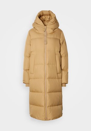 Long camel-colored puffer coat with oversized funnel hood, front zipper, side pockets, and ribbed cuffs against a light background.