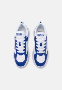 White and blue sneakers with a mesh upper, rubber sole, cushioned tongue, and laces; features logo text on the sides and tongue.