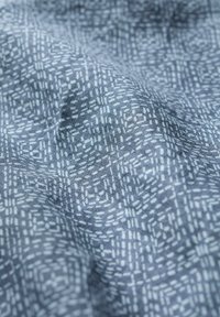 Textiel met textuur in een blauw-grijze achtergrond en een subtiel wit geometrisch patroon, die een gelaagd visueel effect creëert.