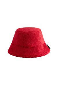 Červený klobouk z materiálu s texturovaným fleece, s širokým okrajem a plochým vrškem, na boku se malou značkovou etiketou.