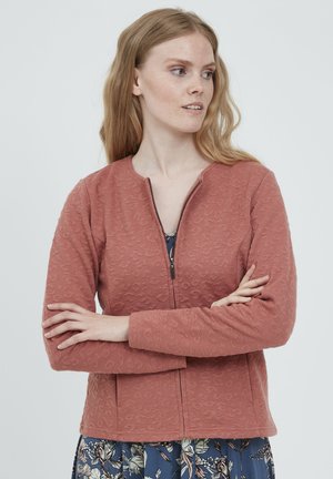 Veste rose avec un motif texturé, encolure ronde et fermeture éclair. Elle a des manches longues et des poches latérales.
