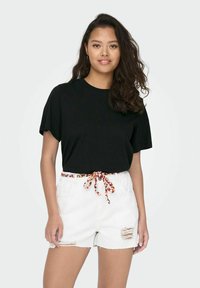 Black short-sleeve t-shirt with a relaxed fit, paired with white denim shorts featuring a colorful drawstring and distressed details.