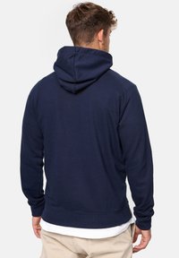 Sudadera azul marino con un bolsillo canguro en el frente, capucha ajustable con cordón y puños y bajo acanalados. Tejido suave con una textura lisa.