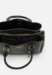 Czarna skórzana torebka o teksturowanym wykończeniu, z złotymi akcentami, podwójnymi uchwytami oraz wewnętrzną kieszenią na zamek. Posiada pikowaną podszewkę.