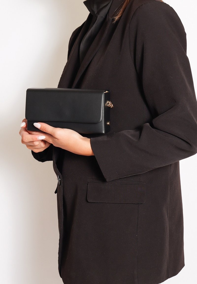 Pochette en cuir noir avec une forme rectangulaire structurée, dotée d'une fermeture à rabat et de subtils accents en métal doré.
