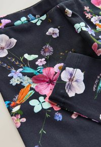 Blomstret stof med vibrante blomster i pink, lilla og blå på en mørk baggrund, med detaljerig og glat tekstur.