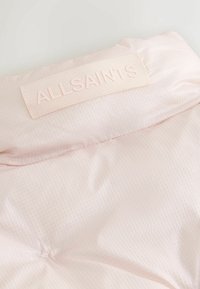 Lichtroze stof met een ruitpatroon, met een gestikte ALLSAINTS-label bovenaan. Gladde, licht gewatteerde oppervlakte.