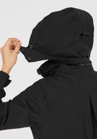 Svart vattentät jacka med avtagbar huva, blixtlåsförsedd front, tryckknappar och strukturerade axlar med en slät yta.
