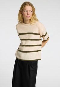 Cremefarvet strikket sweater med olivengrønne vandrette striber, korte ærmer og rund udskæring. Blød tekstur og cropped pasform.