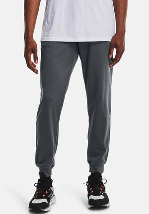 Graue Sporthose aus leichtem Stoff, mit elastischem Bund, schmal zulaufenden Beinen und seitlichen Nahttaschen, kombiniert mit schwarzen Sportschuhen.