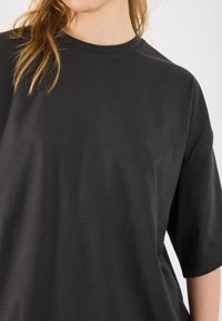 T-shirt nera a maniche corte in cotone con collo a giro. Presenta una vestibilità rilassata e una texture liscia, con dettagli di design minimi.