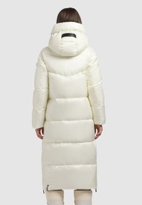 Lang dunfrakke i blød cremefarve med høj krave og aftagelig hætte. Har vandret quiltning og sidelommer med lynlås.