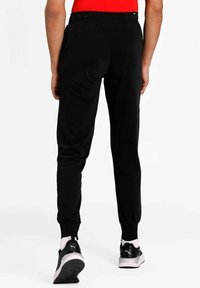 Pantaloni sportivi neri con vita elastica e caviglie elastiche, realizzati in un tessuto morbido, progettati per comfort e libertà di movimento.