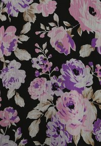 Tecido preto com um padrão floral apresentando rosas cor-de-rosa, lavanda e bege, com folhas verdes e uma superfície texturizada.