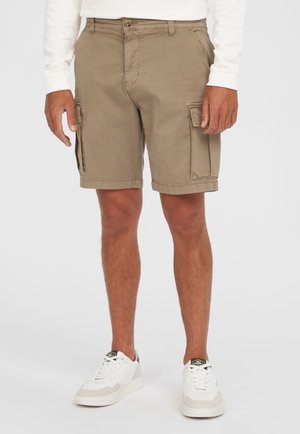Beige Cargo-Shorts mit Seitentaschen, Knopfverschluss und umgeschlagenem Saum. Kombiniert mit weißen Sneakers mit beige Akzenten.
