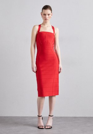 Vestido ajustado rojo con acanalado horizontal, escote cuadrado y tirantes anchos. Combinado con tacones negros de correa en el tobillo. Textura suave.