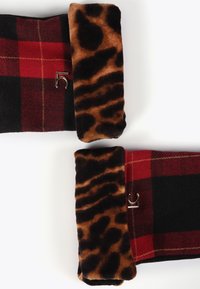 Tessuto a quadri rosso e nero con polsini in pelliccia sintetica con stampa leopardo e piccoli accenti metallici argento su uno sfondo bianco.