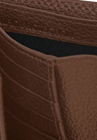 Bruine leren portemonnee met een gestructureerde afwerking, voorzien van kaartsleuven en een zwarte stofvoering. Embleem in het interieur geperst.