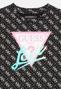 Μαύρο μπλουζάκι με επαναλαμβανόμενο λευκό μοτίβο λογότυπου, με μεγάλο ροζ τρίγωνο και τυρκουάζ κείμενο "LOVE" σε καλλιγραφική γραφή. Καθημερινό σχέδιο.