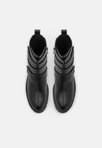Bottines noires avec une finition en cuir lisse, dotées de multiples sangles superposées, de fermetures éclair et d'un design à bout rond. Doublure intérieure douce.