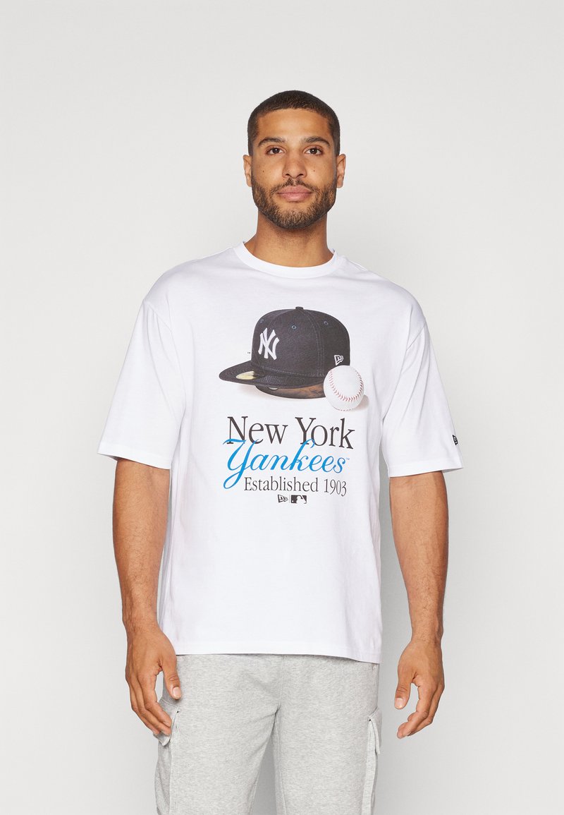Camiseta de manga corta blanca con un gráfico de una gorra de los New York Yankees, una pelota de béisbol y el texto "New York Yankees Established 1903."