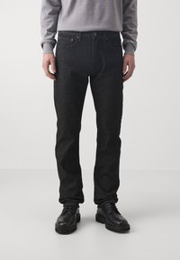 Blugi din denim închis, cu o croială slim, având închidere cu nasture, două buzunare în față și o textură subtilă. Asortați cu pantofi negri cu șireturi.