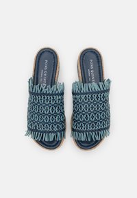 Vävda blåa sandaletter med fransdetaljer, med en texturerad ovandel och en platt, naturlig jute-sula. Varumärket syns i fotbädden.