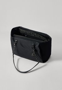 Borsa tote nera in nylon con una superficie liscia, dotata di doppie maniglie, chiusura con zip e un dettaglio con logo. All'interno presenta più scomparti.