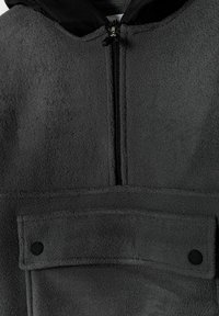 Giacca in pile grigia con cappuccio nero, zip verticale e tasca frontale con bottone. Texture morbida e materiale soffice in tutto.