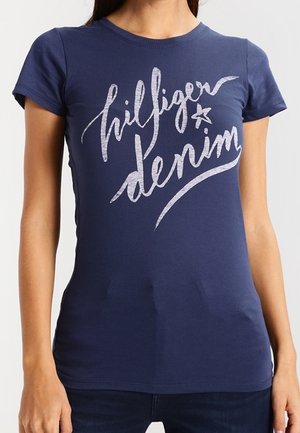 T-shirt aderente blu navy a maniche corte con testo in corsivo bianco "hilfiger denim" e grafica a stella sul davanti.