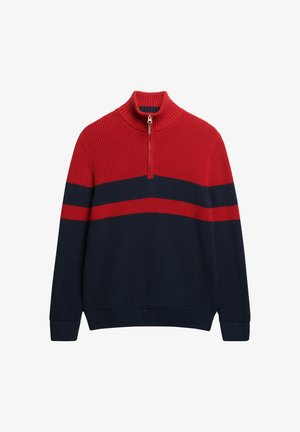 Pull à col zippé rouge et bleu marine avec texture côtelée, présentant des rayures horizontales et un col montant. En mélange de coton.