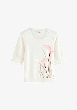 Pull en coton blanc avec des manches courtes bouffantes, un col rond et un design floral en rose pâle et vert sur le devant.