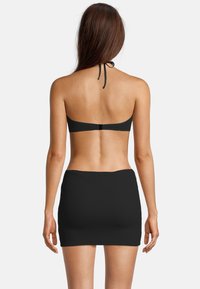 Zwarte bikinibovenstuk met halternekontwerp, gecombineerd met een bijpassende zwarte geribde rok. Gladde textuur; minimale hardware-details.