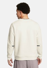 Cremfarbener Sweatshirt mit langen Ärmeln, rundem Halsausschnitt und strukturiertem Stoff. Verfügt über einen schwarzen Akzent am linken Ärmel und gerippten Bündchen.