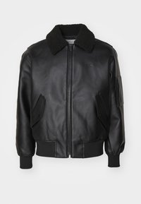 Μαύρο δερμάτινο μπουφάν bomber με ψεύτικη επένδυση από γούνα στον γιακά, κλείσιμο μπροστά με φερμουάρ, πλαϊνές τσέπες και ριμπ μανσέτες και στρίφωμα. Διακριτική λεπτομέρεια με λογότυπο.