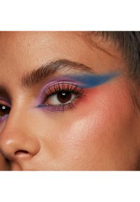 Nahaufnahme eines Auges mit lebend in blauen, lila und korallenfarbener Lidschatten, definierten Wimpern und glatter, strahlender Hauttextur.
