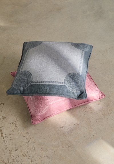 Două perne decorative: una gri cu modele circulare și un bordaj, cealaltă roz cu un design similar. Textură moale, formă pătrată.