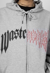 Grijze hoodie van een katoenmixstof met een capuchon met trekkoord, zwarte tekst "wasted" en een rode, vlamachtige grafische afbeelding.