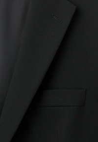 Blazer nero realizzato in tessuto testurizzato, dotato di un colletto elegante, dettagli di cucitura sottili e una tasca singola sul davanti.