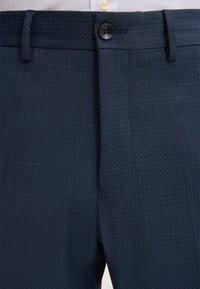 Navyblaue, strukturierte Hosen mit geradem Schnitt, Knopfverschluss und seitlichen Taschen, aus leichtem, atmungsaktivem Stoff gefertigt.