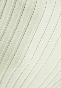 Detalj av off-white ribbat stickat tyg med jämnt fördelade vertikala texturerade linjer.