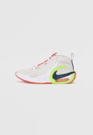 Sneakers ar gaiši pelēku acs augšdaļu, sarkaniem akcentiem, neona zaļu papēdi un melnu Swoosh logo. Iespējo komfortablu zoli ar redzamu gaisa vienību.